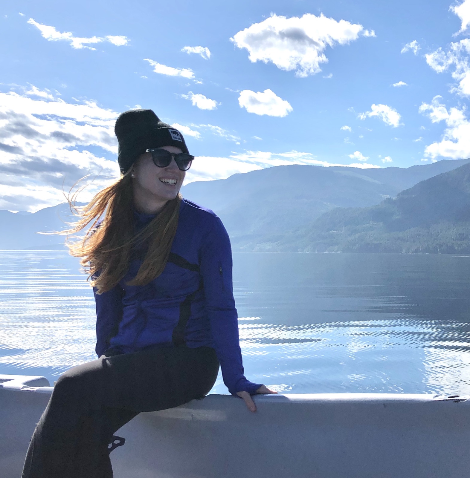 Annika smiling on a boat with mountains and water behind her